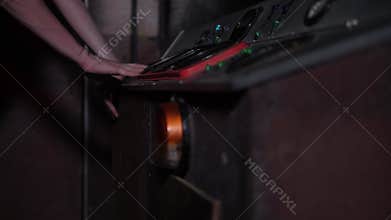 A woman presses buttons on an old control panel in a subway car, quest.