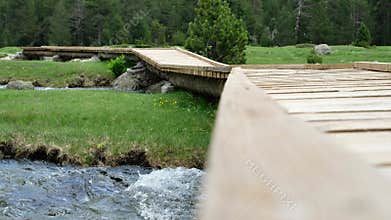 Winding Wooden Bridge-trail over Mountain Streams on Green Meadow. Alpine Landscape.