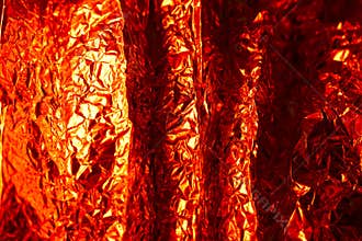Close up view of crumpled shiny red foil reflecting light in an artistic arrangement