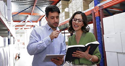 Professional man and woman shaking hands, standing in warehouse aisle