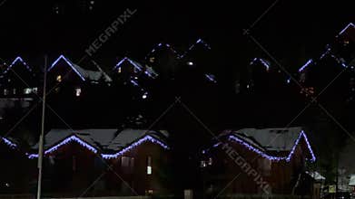 Snowy roofs with Christmas lights twinkling in the night
