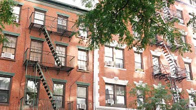 New York City building architecture, Manhattan. Residential house exterior. Red brick, fire escape.