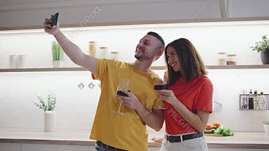 A cheerful couple happily poses for a fun selfie in their stylishly designed kitchen, capturing a delightful moment of