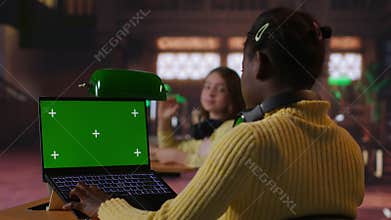 Preteen scholar works on a school assignment with green screen in the library