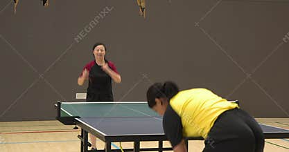 Playing table tennis, women competing in indoor sports facility, focusing on game