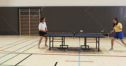 Playing table tennis, two people competing in indoor sports hall