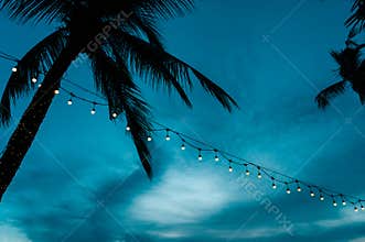 light bulbs on string wire decoration at the party event festival on the beach at sunset. Outdoor holiday background. Copy space