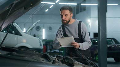 Auto mechanic professional technical expert Caucasian man male checking car manual maintenance write checklist on