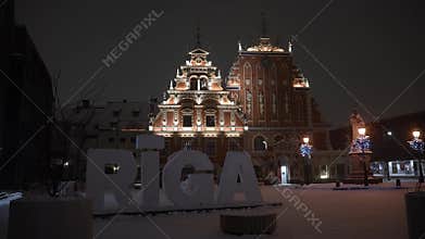 Snow falling at night in Riga old town with house of the blackheads