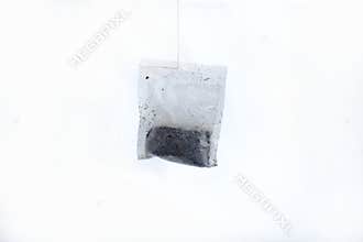 Single tea bag hanging on a white background.