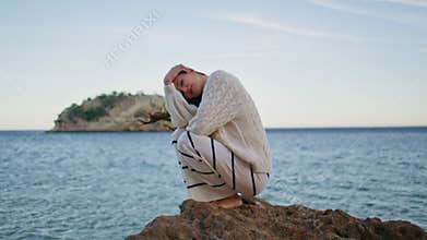 Beautiful model posing seascape crouching on coastal rock. Woman enjoying ocean