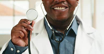 Friendly Male Doctor Holds Stethoscope and Smiles, Close-Up in Hospital Setting