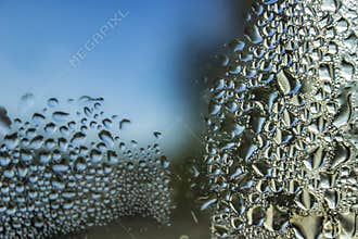 Abstract water droplets on glass with blue sky background