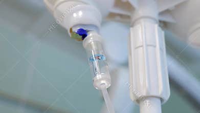 Medical drip is delivering anesthesia to a patient during surgery. The intravenous needle is connected to a tube