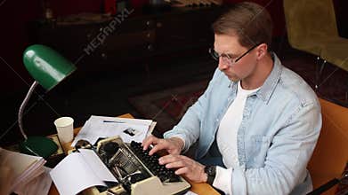 Soft-focused image of an author battling writer's block at his cluttered desk