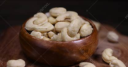 large cashew nuts are scattered on a larch board