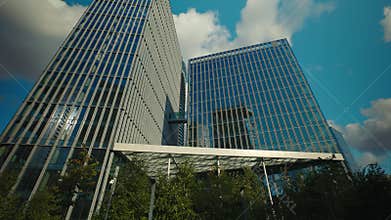 Corporate center buildings with glass facades in city under blue sky with clouds