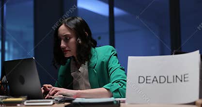 Woman office worker sits at desk and tries to finish assignment