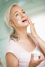 Middle aged woman applying face cream