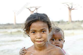 Madagascar-shy and poor african girl with infant on her back