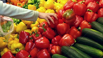 Woman selecting red and yellow peppers in grocery store
