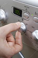 Woman Selecting Cooler Temperature On Washing Machine To Save En