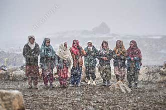 Old ladies in the middle of snow waiting animals to return from pasture.