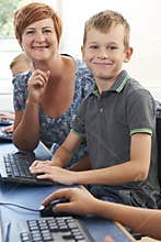 Male Elementary Pupil In Computer Class With Teacher