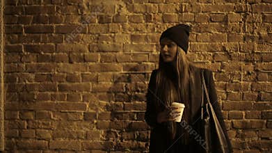 Girl teenager in the street at night drinking coffee and waiting