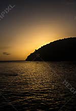 Sunset over the water at Martinique with mountain silhouette and calm sea