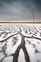 Paths of snow and water on seashore near La Rochelle at sunset create a unique landscape after a winter thaw and low tide