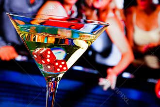 Red dice in the cocktail glass in front of gambling table