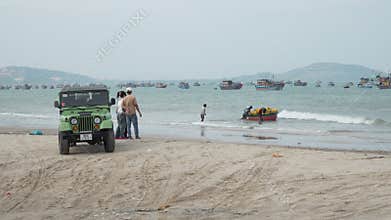 Tourists watch fishermen launch a round boat on Mui Ne beach
