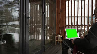 A man looks at a green laptop screen.