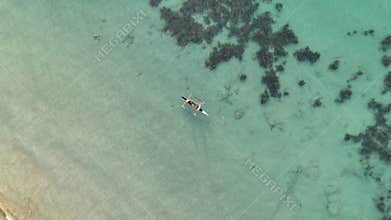 Overhead helix drone shot circling two fishermen casting a net from a