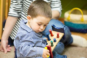 Little child boy playing in kindergarten in Montessori Class.