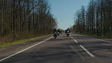 Steadicam shot of motorcycle convoy riding through a forest road