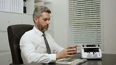 Businessman working on laptop with stacks of money in office. Business concept with cash and digital work. Banker in office