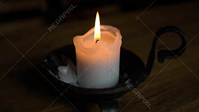 Candle in a candlestick on a wooden table