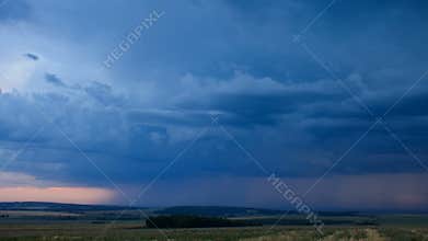 Storm dark clouds over field an sunset.
