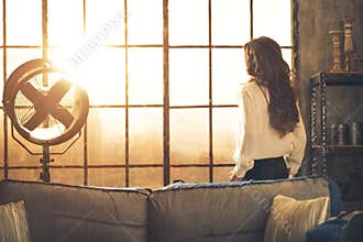 Young woman looking in window in loft apartment