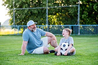 Dad and son having fun while practicing football outdoors.