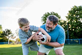 Dad and son having fun while practicing football outdoors.
