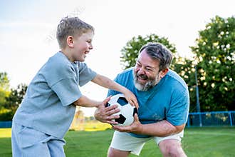 Dad and son having fun while practicing football outdoors.