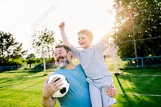 Dad and son having fun while practicing football outdoors.