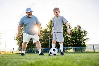 Dad and son having fun while practicing football outdoors.