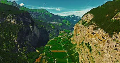 Establishing shot of Switzerland. Aerial view of the green meadows of Switzerland, with the Alps and clouds in the