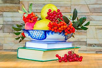 Still life: books and fruit and berries in a beautiful vase.