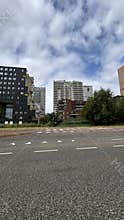 Modern mixed residential and office buildings along urban street under cloudy sky