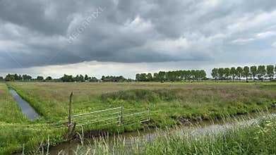 Rural Amsterdam, Dutch farmland panorama under heavy storm clouds with canal